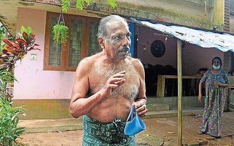 Thankachan, a retired government official suffering from age-related ailments, stands in front of his home, his life’s investment, that he cannot salvage