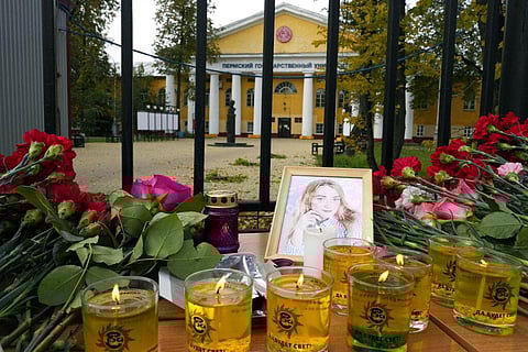 Flowers, candles and a portrait of one of victims are displayed on a table outside the Perm State University. (Photo | AP)