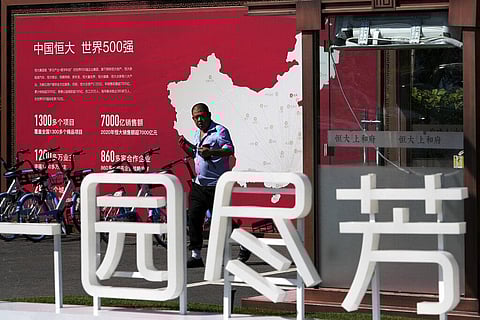 A security guard walks by a map showing Evergrande development projects in China at an Evergrande new housing development in Beijing. (Photo | AP)