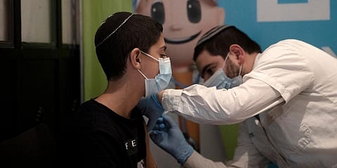 A 14-year-old Israeli receives a booster shot of the coronavirus vaccine at Clalit Health Service's center in the Cinema City complex in Jerusalem. (Photo | AP)