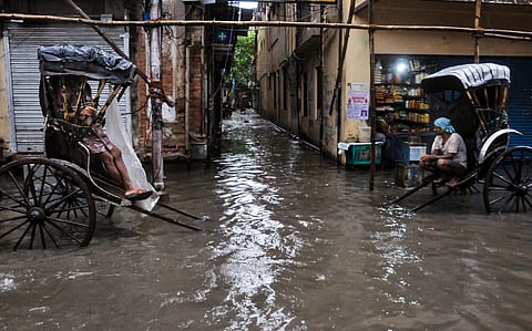 Hand-pulled rickshaw drivers wait for passengers on a waterlogged road after overnight rains, in Kolkata on Wednesday. (Photo | PTI)