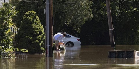 A woman scoops out the water from her front yard after a night of high winds and rain from the remnants of Hurricane Ida in New York on September 2, 2021. (Photo | AFP)