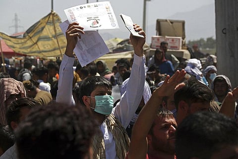Hundreds of people gather, some holding documents, near an evacuation control checkpoint on the perimeter of the Hamid Karzai International Airport. (Photo | AP)