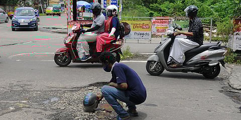 A passerby is keeping an unused helmet at a pothole in the stadium link road in Ernakulam. (Photo| A Sanesh, EPS)