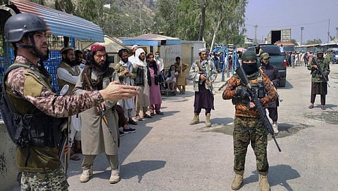 A Pakistani paramilitary soldier, left, and Taliban fighters stand guard on their respective sides, at a border crossing point between Pakistan and Afghanistan. (Photo | AP)