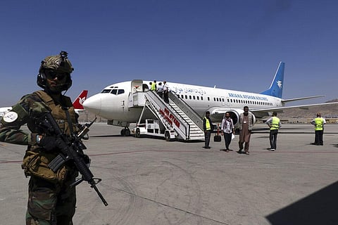 A Taliban soldier stands guard as passengers disembark on arrival from Kandahar, at Hamid Karzai International Airport in Kabul. (Photo | AP)