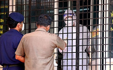A relative of the person admitted in Nipah traige handing over the materials for the patient to health worker at Kozhikode Medical College. (Photo | T P Sooraj, EPS)