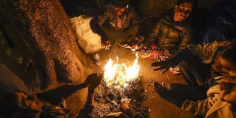 A group of people warm themselves at a bonfire on a cold winter evening in New Delhi. (Photo | PTI)