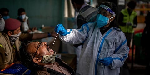 A health worker collects a swab sample of a passenger to test for COVID-19 at a train station in New Delhi. (Photo | AP)
