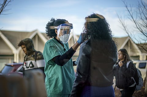 A COVID-19 technician, performs a test outside Asthenis Pharmacy in Providence. (Photo | AP)