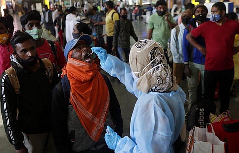 A health worker collects a swab sample from a traveler at the Chhatrapati Shivaji Maharaj terminus to test for the coronavirus before allowing him to enter the city, in Mumbai. (Photo | AP)