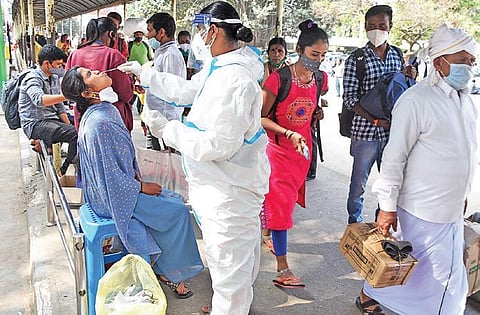 A health worker collects swab samples from passengers at a bus stand in Bengaluru on Wednesday, amid fear of spread of Omicron | VINOD KUMAR T