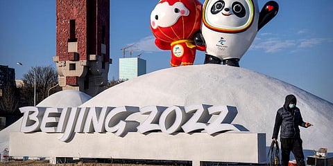 A worker wearing a face mask to help protect against the coronavirus walks past a display of the Winter Paralympic mascot Shuey Rhon Rhon. (Photo | AP)