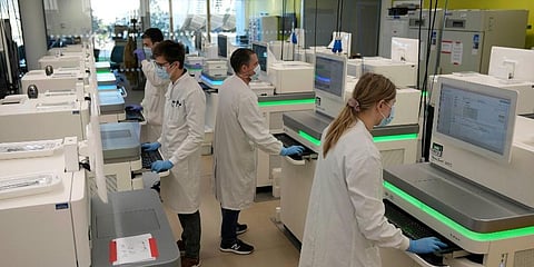 Research assistants work at sequencing machines analyzing the genetic material of COVID-19 cases at the Wellcome Sanger Institute. (Photo | AP)