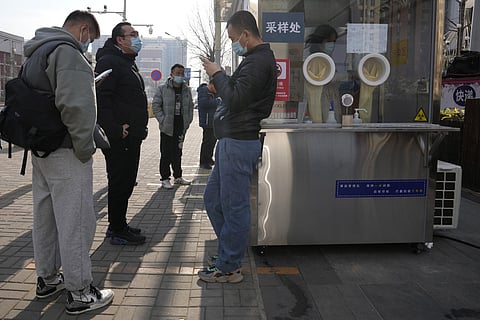 Workers and residents stand near a nuclei test station in Beijing, China, Tuesday, Jan. 18, 2022. The first reported case of the omicron variant has prompted stepped-up measures in Beijing. (AP)
