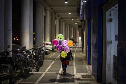 A balloon seller walks in a deserted shopping area amid restrictions imposed due to rising numbers of COVID-19 cases, on New Year's Eve in New Delhi. (Photo | AP)