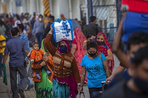 Passengers wearing face masks as a precaution against coronavirus arrive at a train station in Mumbai. (Photo | AP)