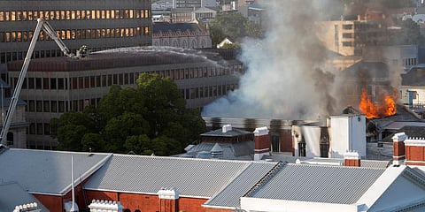 Firemen spray water on flames erupting from a building at South Africa's Parliament in Cape Town. (Photo | AP)