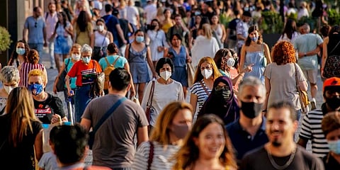 People wearing face masks to protect against the spread of coronavirus walk along a street in downtown Barcelona. (Photo | AP)