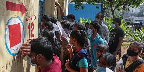 A man tired of waiting leans against the wall as people crowd the counter of a government hospital for their COVID-19 tests in Hyderabad. (Photo | AP)
