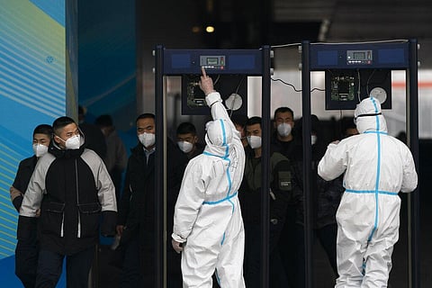 Two security personnel in protective gear set up metal detectors at the main media center at the 2022 Winter Olympics, Monday, Jan. 24, 2022, in Beijing. (Photo | AP)