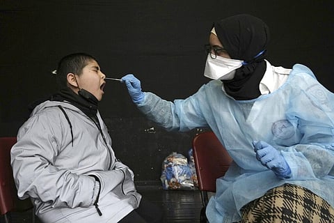 A Palestinian child reacts to a nasal swab by as a medic from the Magen David Adom emergency service administers a rapid antigen coronavirus test. (Photo | AP)