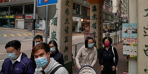 People wearing face masks walk along a street in Hong Kong. (Photo| AP)