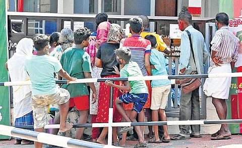 A group of people, including children, waiting to collect the food packets being distributed by the Joint Council