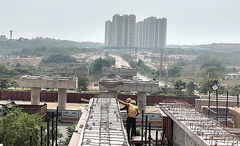 Workers carry out construction work for the trumpet-shaped interchange at Kokapet in Hyderabad on Sunday