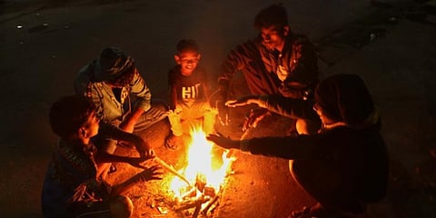 Children sitting around a bonfire to keep themselves warm in Bhubaneswar. (Photo| Irfana, EPS)