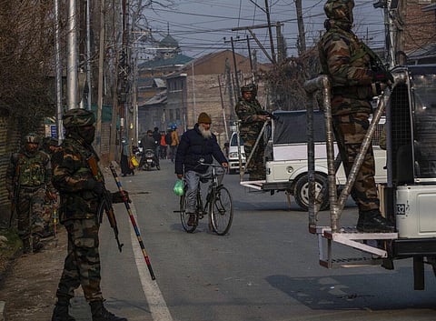 An elderly Kashmiri man rides on his bicycle as government forces guard near the site of shootout that killed two suspected rebels on the outskirts of Srinagar. (Photo | AP)