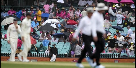 Spectator open their umbrellas as rain begins to fall and players leave the field during the Ashes cricket test match between England and Australia in Sydney, Wednesday, Jan. 5, 2022. (Photo | AP)