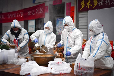 In this photo released by China's Xinhua News Agency, volunteers wearing protective suits package meals for delivery to people under lockdown in Xi'an. (Photo | AP)