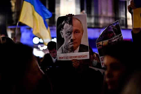 A demonstrator holds a sign depicting Adolf Hitler and Russia's president Vladimir Putin during a protest against Russia's military operation in Ukraine, in Barcelona on February 24, 2022. (Photo | A