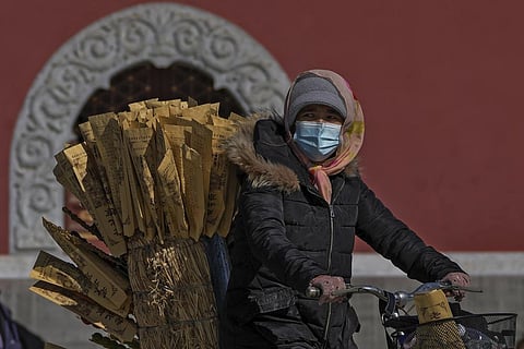 A vendor rides on a bicycle selling sugar-coated Chinese haw at a public park in Beijing, Monday, Oct. 10, 2022. (Photo | AP)