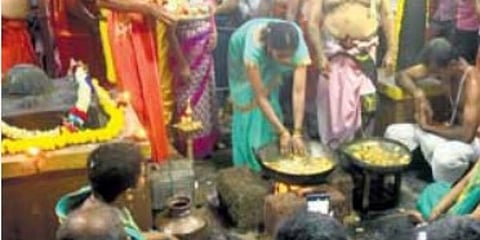 A devotee dips her hands in hot oil.