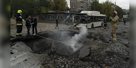 Firefighters and police officers work on a site where an explosion created a crater on the street after a Russian attack in Dnipro, Ukraine. (Photo | AP)