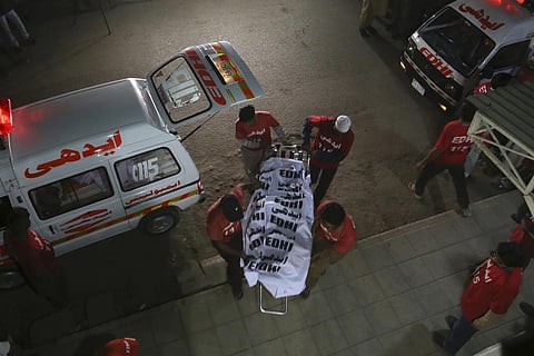 Volunteers transport a body of a passenger who was killed in a bus fire in Karachi, Pakistan, Thursday, Oct. 13, 2022. (Photo | AP)