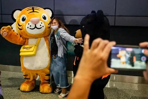 A woman, part of the first tourist group arriving from Thailand, poses with a mascot at Taoyuan International Airport in Taoyuan on October 13, 2022. (Photo | AFP)