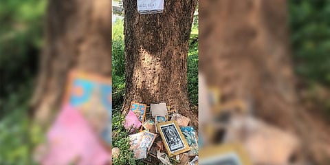 Residents post warning poster on a tree which has now become dumping point of broken photo frames of Gods in Navanagar area of Hubballi (Photo | Express)