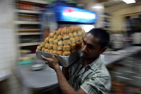 A man carries a plate of bun maska in an Irani cafe. (File Photo | AFP)