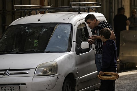 Palestinian kids look at a damaged car following an Israeli raid in the occupied West Bank city of Nablus. (Photo | AP)