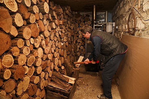 Tudor Popescu chops fire wood he uses for heating in a storage room attached to his home in Chisinau, Moldova, Oct. 15, 2022. (Photo|AP)