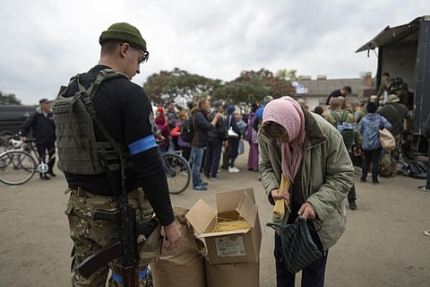 A Ukrainian serviceman of Sophia battalion distributes humanitarian aid to a local woman in the recently liberated town of Izium, Ukraine, Sunday, Oct. 2, 2022. (Photo | AP)