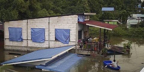 A resident paddles through floodwaters to reach the second story of his home in Ubon Ratchathani province, northeastern Thailand. (Photo | AP)