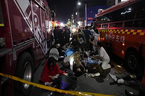 Injured people are helped at the street near the scene of a deadly stampede in Seoul, South Korea, on October 30, 2022. (Photo | AP)