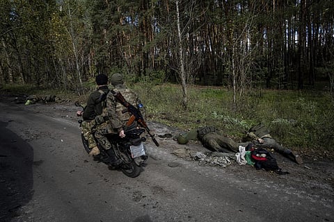 Sad remnants of war: Ukrainian servicemen drive a motorbike past bodies of Russian serviceman in the recently recaptured town of Lyman, Ukraine, Monday, Oct. 3, 2022. (Photo | AP)
