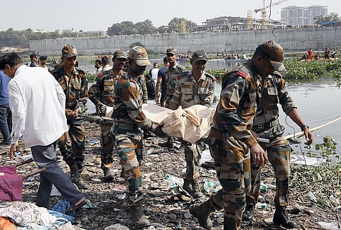 Armed Forces personnel carry the dead body of a victim, recovered during a rescue operation after an old suspension bridge over the Machchhu river collapsed, in Morbi. (Photo | PTI)