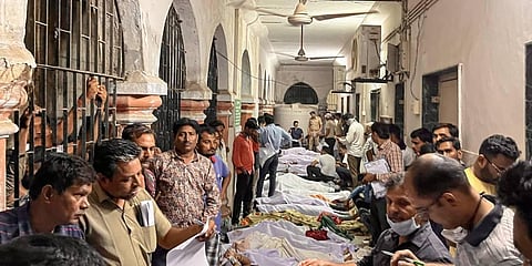 Family members and relatives near the dead bodies of victims who were killed after the collapse of a suspension bridge over the Machchhu river, at Civil Hospital in Morbi district. (Photo | PTI)