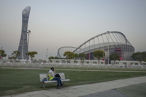 A man sleeps on a bench before his early morning shift, in front of Khalifa International Stadium, in Doha, Qatar, on Oct. 15, 2022. (Photo | AP)